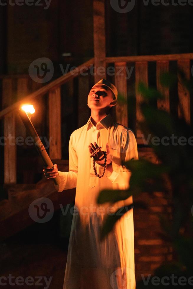 A Muslim man standing with the fire torch in her hand at the front of the village photo
