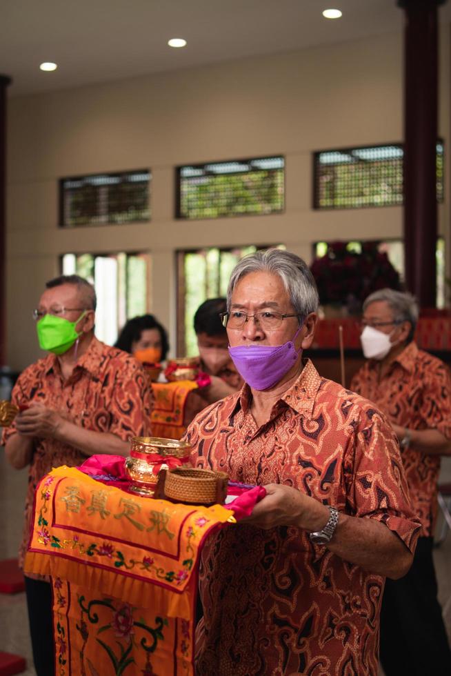 Bandung City, Indonesia, 2022 - the old man brings the offerings to the altar while praying with the monks photo