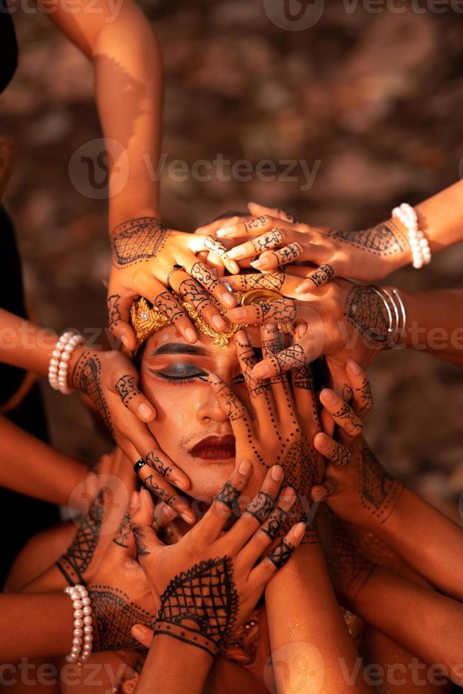 caras de hombre triste cubiertas por muchas manos con tatuajes de henna mientras usa una corona de oro foto