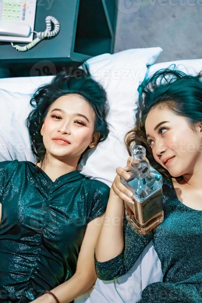 Asian women holding an alcohol bottle in their hand in the bedroom photo