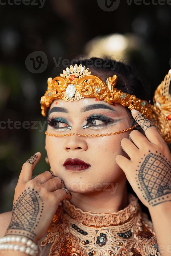 Beautiful Indian bride wearing a golden crown and a golden necklace with tattoos on her hands photo
