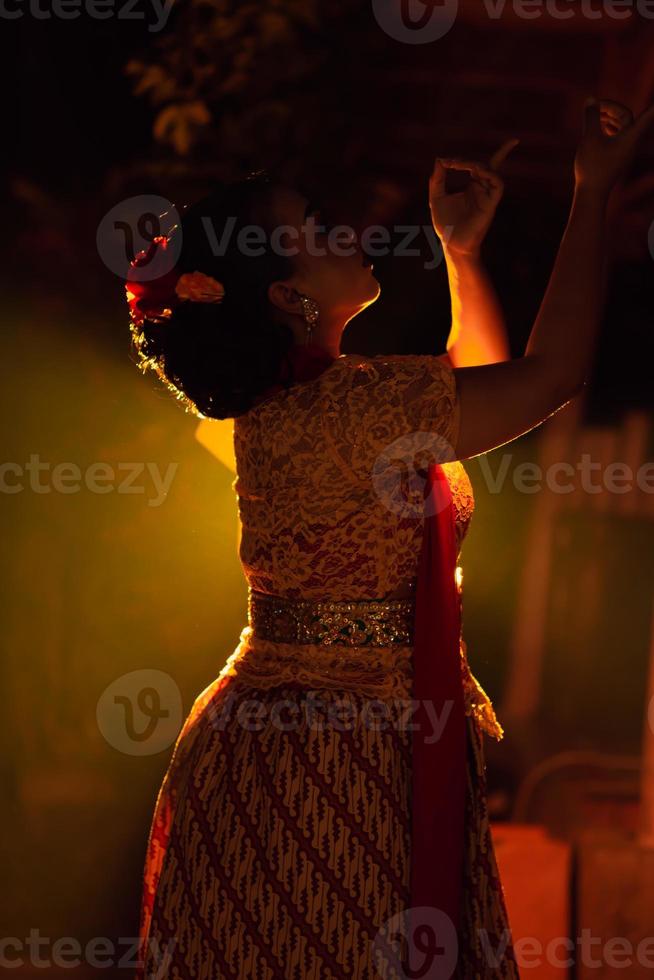 Balinese women wearing cultural clothes while posing in front of the lighting with dancing movements photo