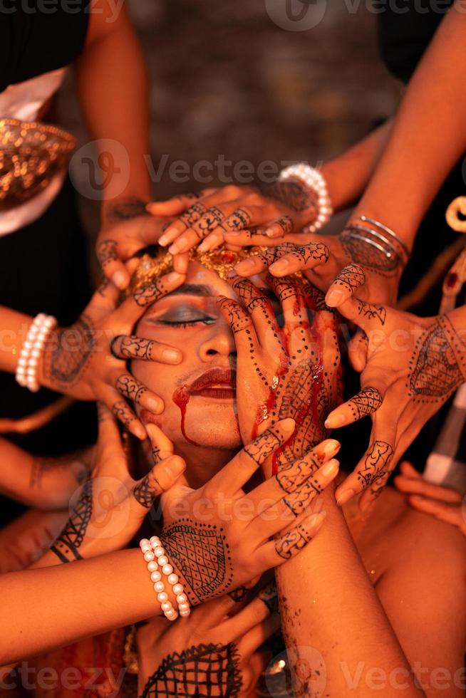 Sad Man Faces covered up by a lot of hands with henna tattoos while wearing a gold crown photo