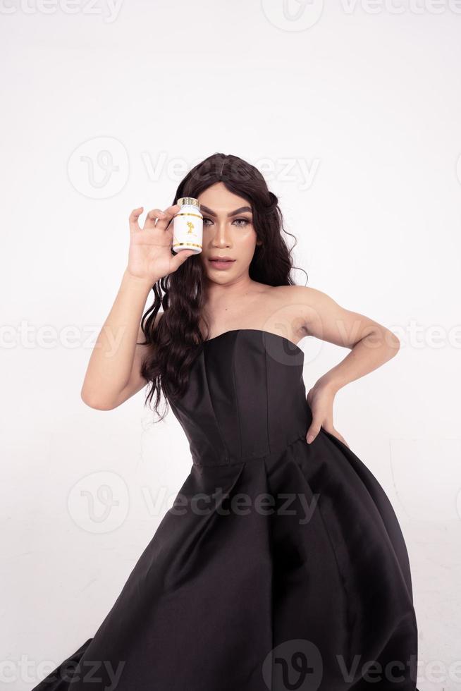 glamor woman holding a skincare jar in her hands with black hair and dress inside the white room photo