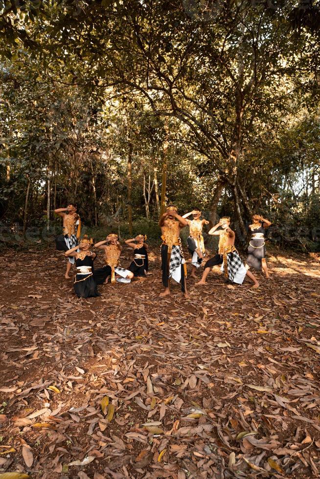 Javanese dance in golden costumes while wearing a makeup pose together nearing the brown leaves photo