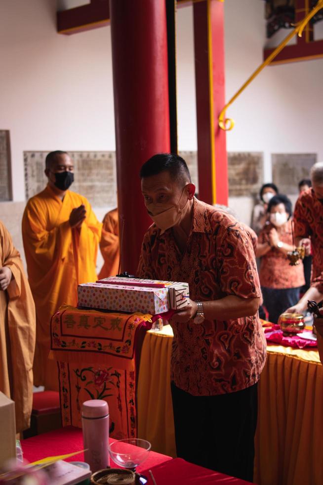 Bandung City, Indonesia, 2022 - the old man brings the offerings to the altar while praying with the monks photo