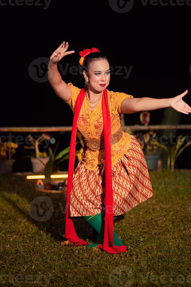 bailarina balinesa con un traje naranja y maquillada posando como una bailarina con el pelo negro foto