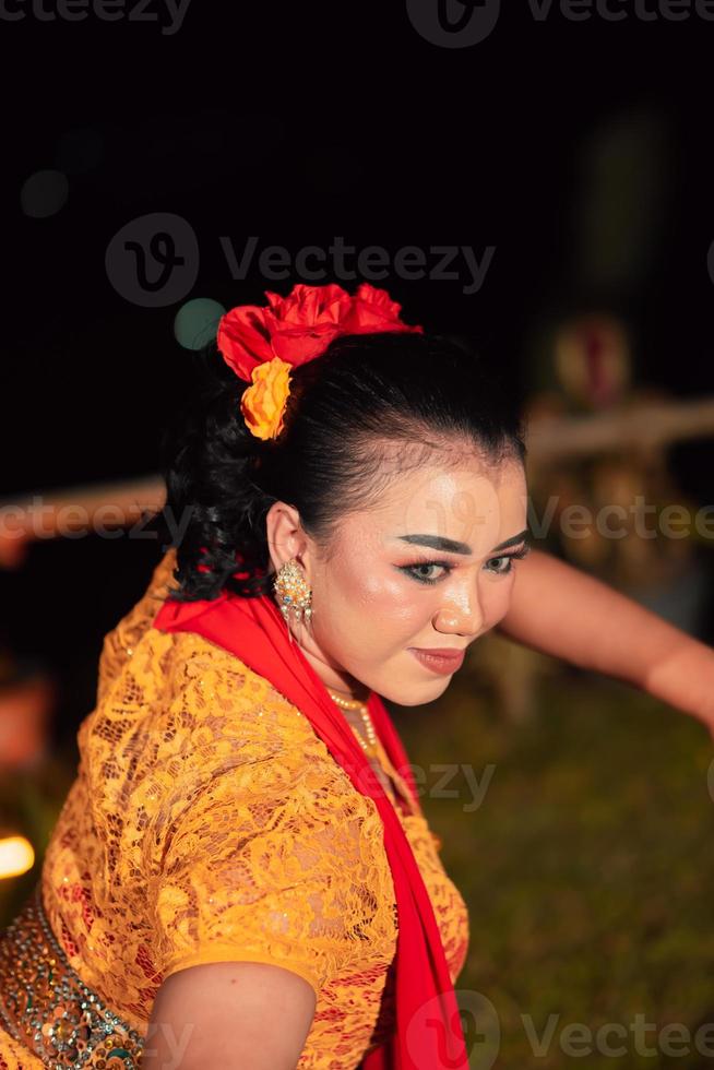 Beautiful face of an Indonesian woman in makeup while dancing a traditional dance in an orange costume during the festival photo