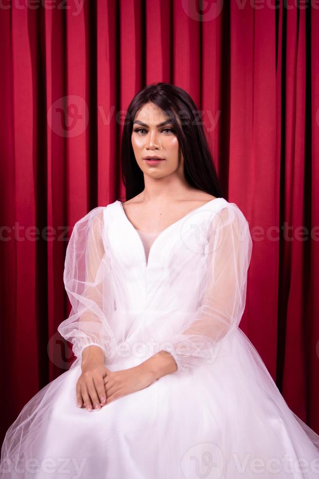 Luxury Asian woman in a white dress with a red curtain in the background photo