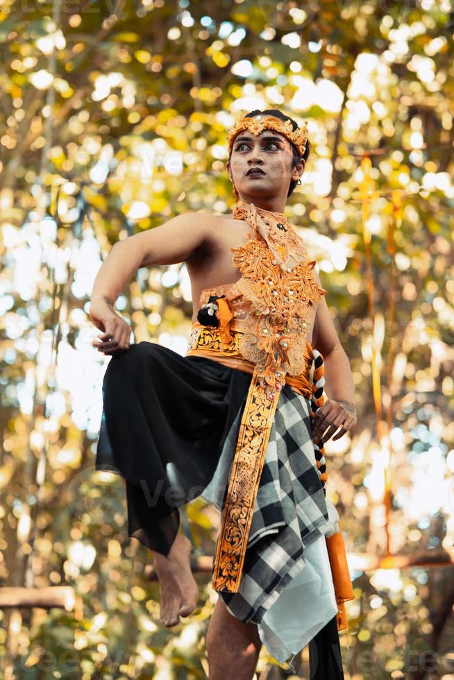 Balinese man raise their feet and dance pose in golden costumes with golden crowns photo