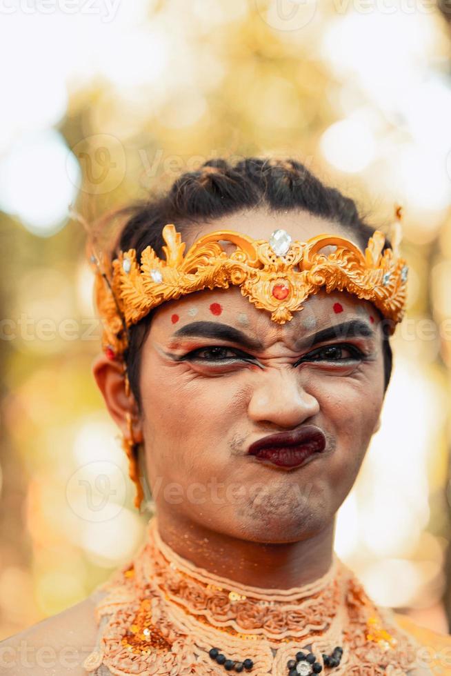 portrait of a Javanese man wearing a gold crown and gold necklace in makeup shirtless photo