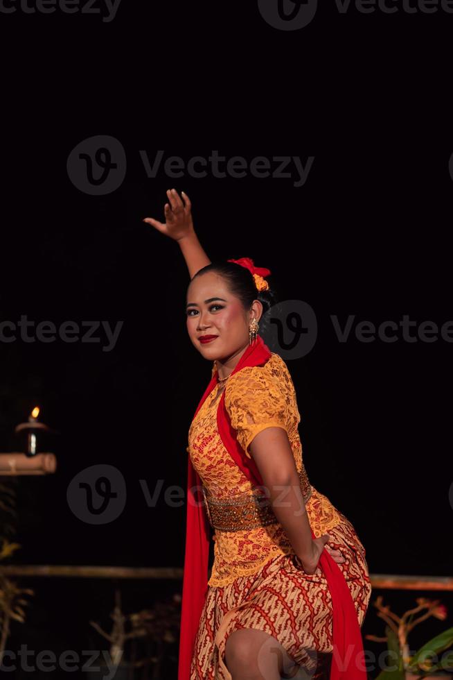 Asian woman performing a traditional dance called jaipong in Indonesia with a yellow dress and red scarf photo