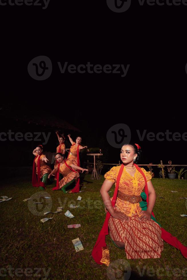 un grupo de bailarines indonesios actuando en el escenario con una bufanda roja y un vestido naranja tradicional dentro del festival foto