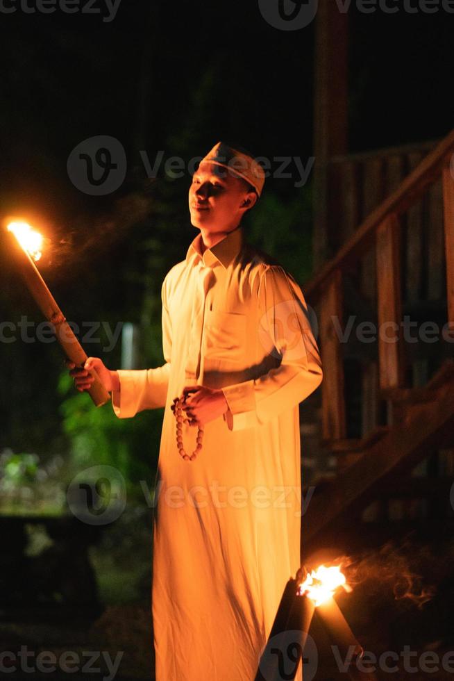 A Muslim man standing with the fire torch in her hand at the front of the village photo