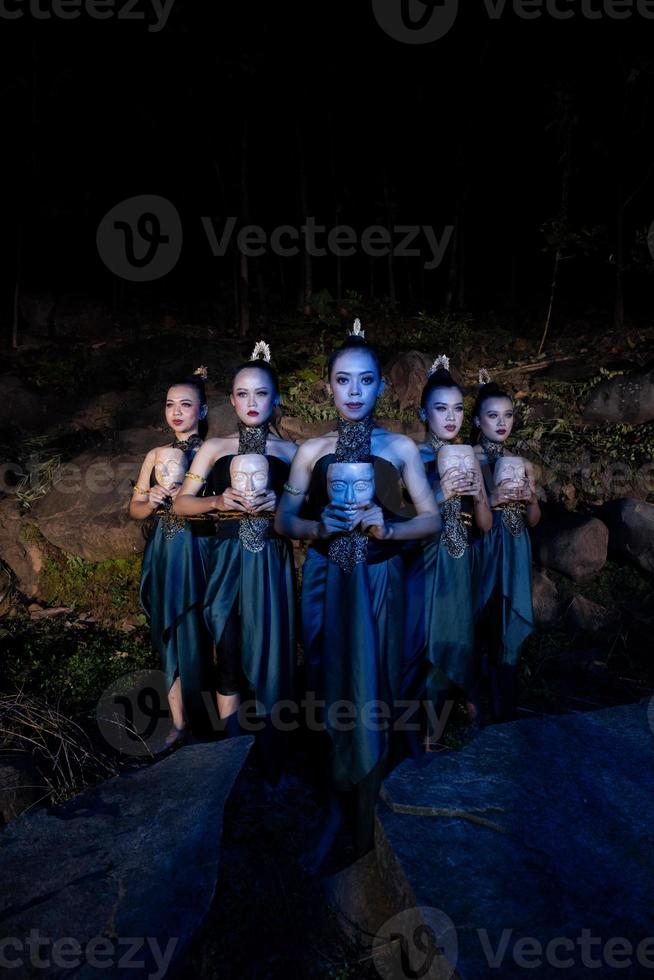 A Group of Balinese woman line up with the wooden mask in their hands while wearing a traditional dance costumes photo