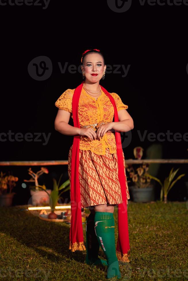 Indonesian woman with a gorgeous orange batik dress wearing a red scarf and red lips on her face photo