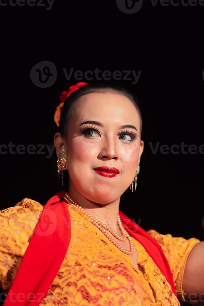 mujer indonesia maquillada con labios rojos usando un collar dorado y aretes dorados foto