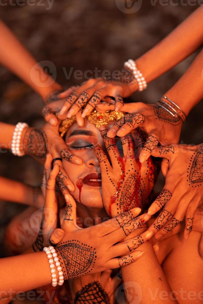 Sad Man Faces covered up by a lot of hands with henna tattoos while wearing a gold crown photo