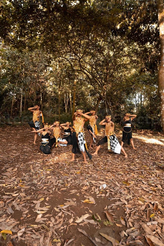 Javanese dance in golden costumes while wearing a makeup pose together nearing the brown leaves photo