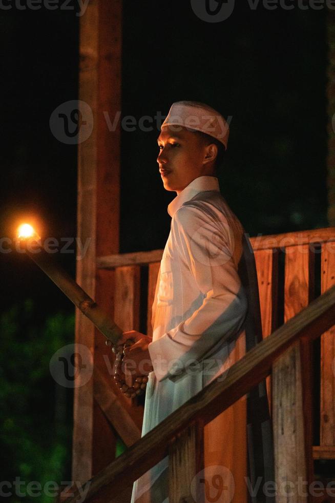 A Muslim man standing with the fire torch in her hand at the front of the village photo