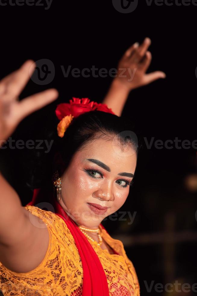 An Asian Traditional dancer in an orange dress with a red scarf and makeup performing at the dance festival photo