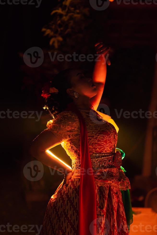 Balinese women wearing cultural clothes while posing in front of the lighting with dancing movements photo