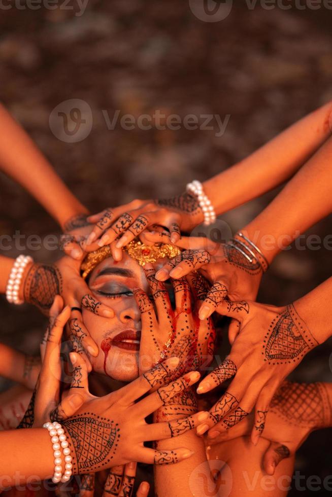 Sad Man Faces covered up by a lot of hands with henna tattoos while wearing a gold crown photo