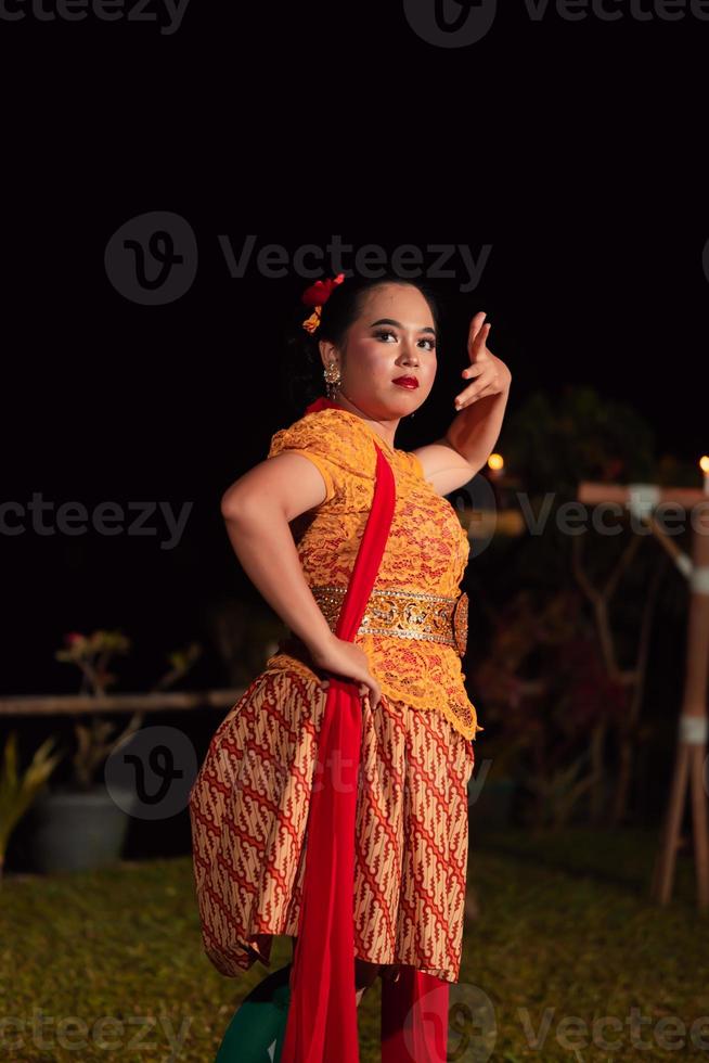 Balinese dancers in yellow color traditional costumes present the dance in front of visitors in a Bali photo