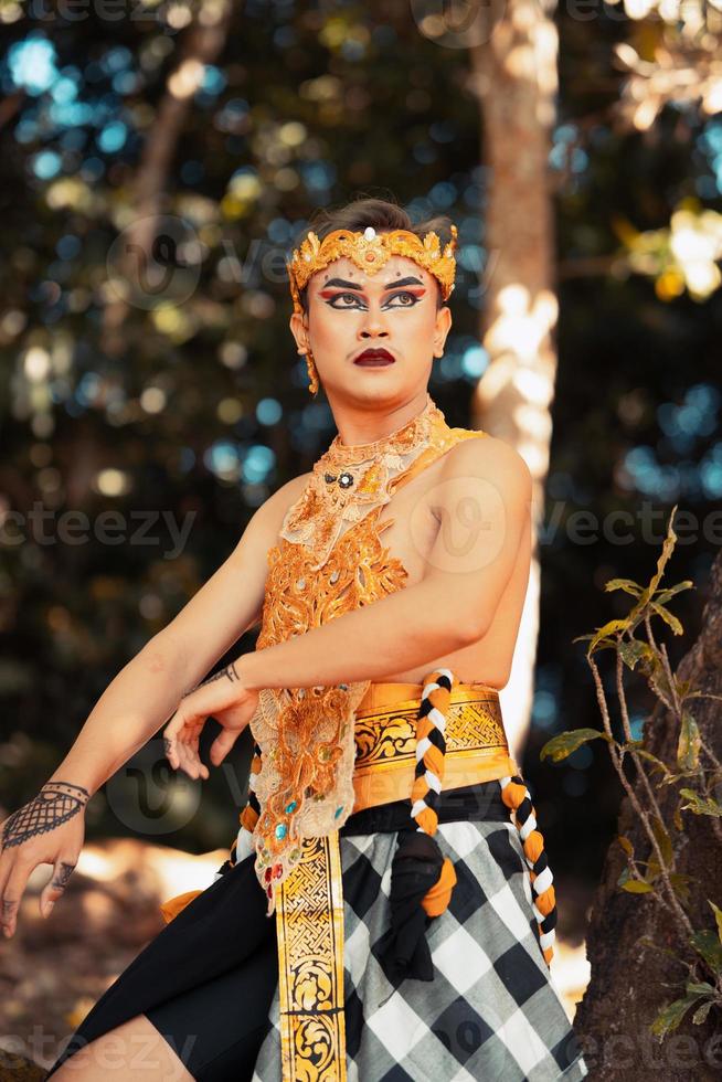 Balinese dancer performs the dance in golden costume and golden crown inside the temple photo