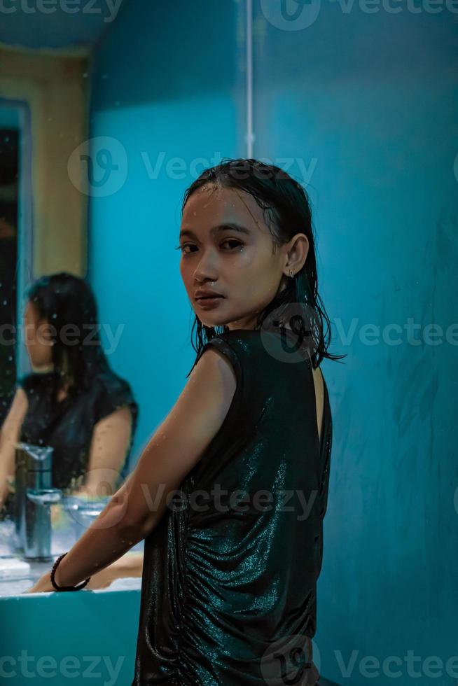 un retrato de una chica mojada parada frente al espejo y la pared azul con caras sonrientes foto