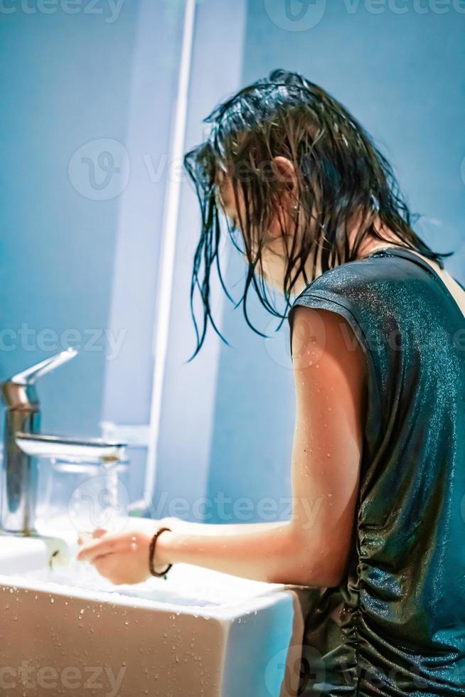 A Young Woman washes her hands in the white sink from the virus Covid-19 photo