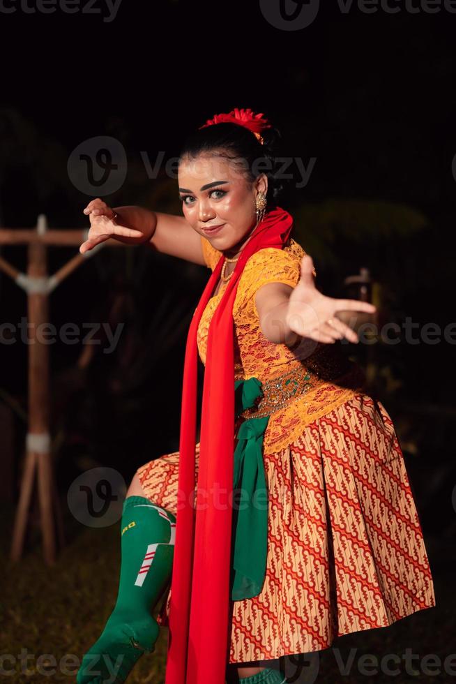 Balinese woman in traditional orange dress dancing with a red scarf while performing dancing photo