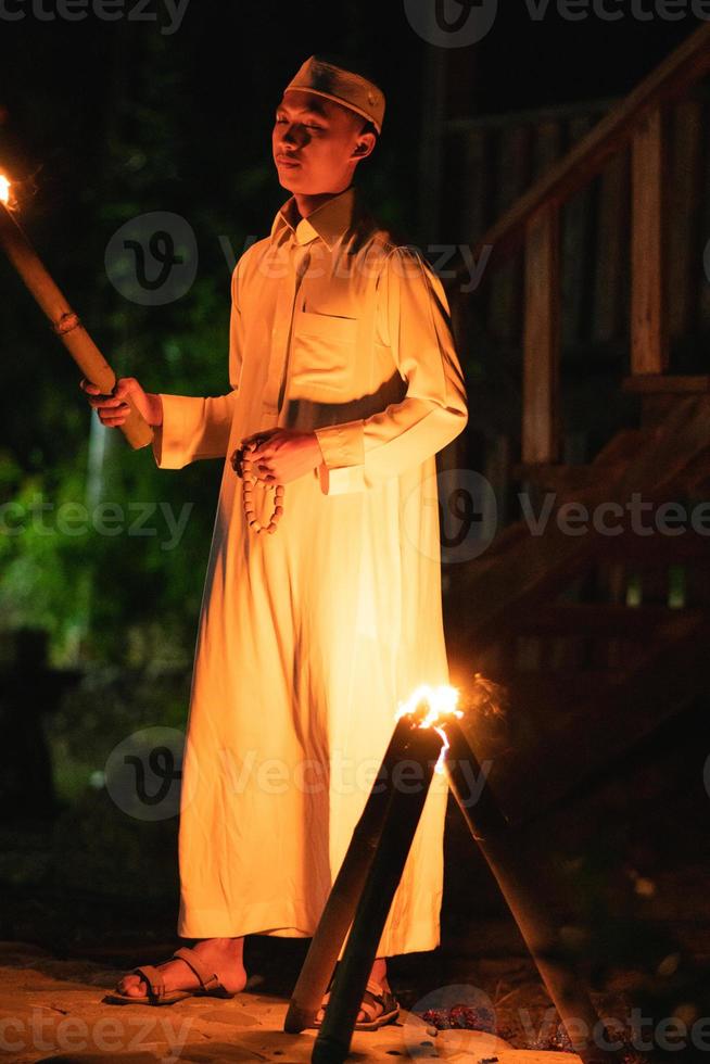 A Muslim man standing with the fire torch in her hand at the front of the village photo