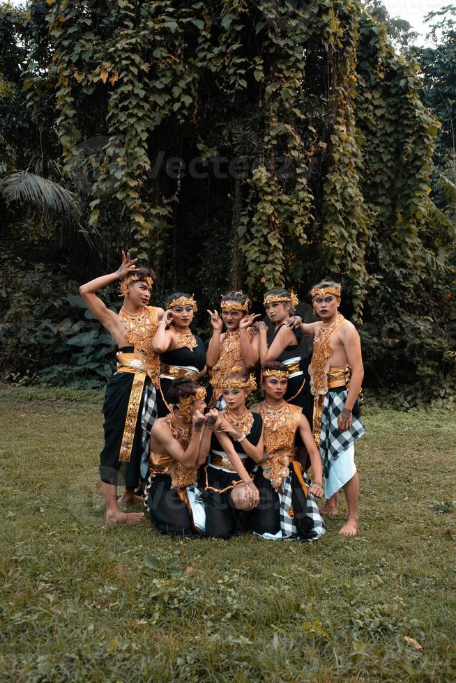 un grupo de asiáticos divirtiéndose mientras toman una sesión de fotos con un traje de baile dorado frente a la jungla