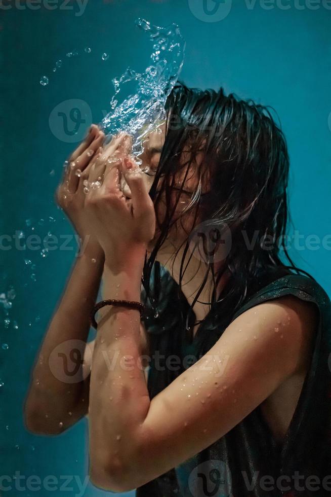 Portrait of Indonesian woman taking a bath in the shower while wearing a black dress photo