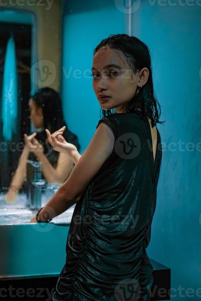 un retrato de una chica mojada parada frente al espejo y la pared azul con caras sonrientes foto