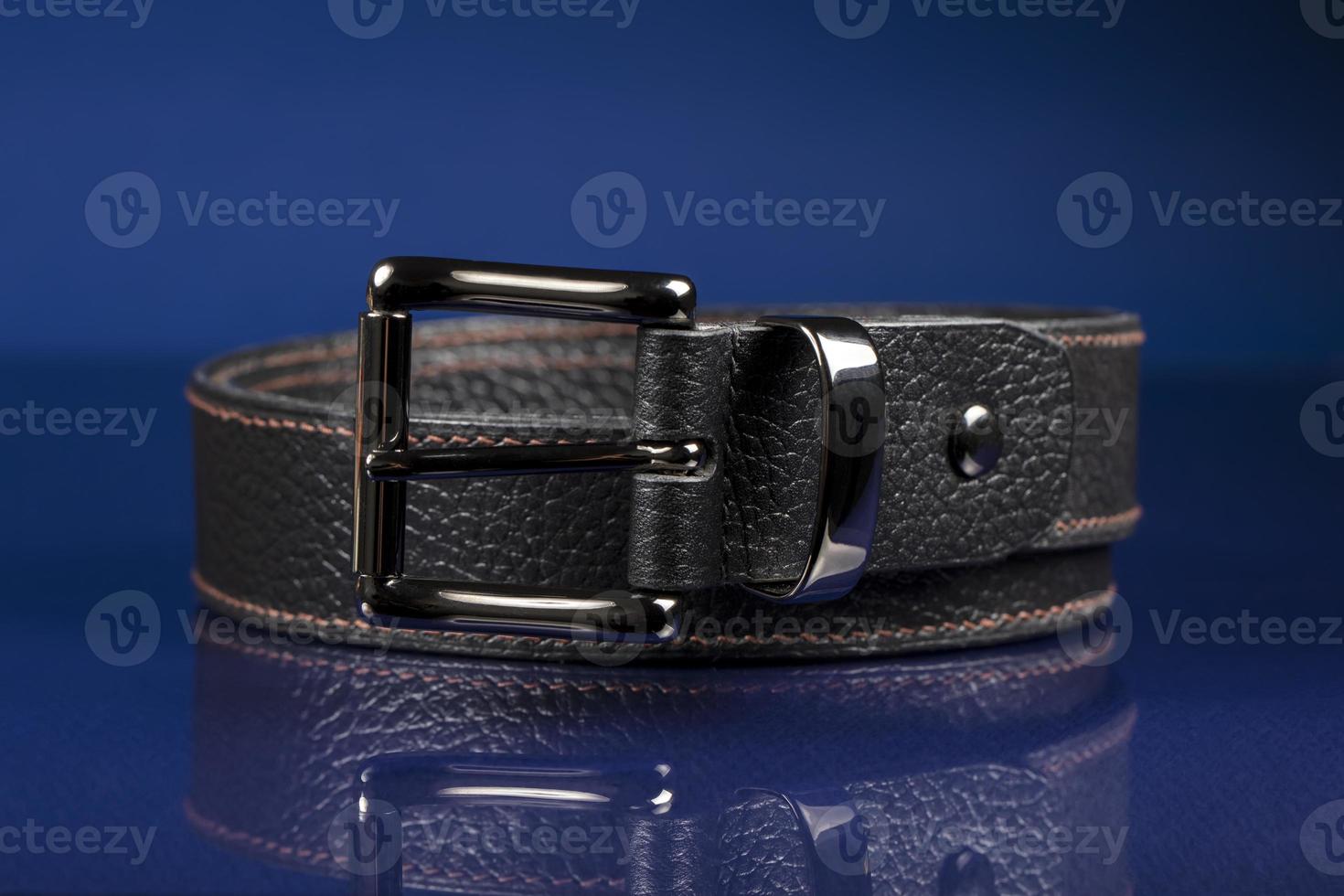 Black leather belt on a dark blue background. photo