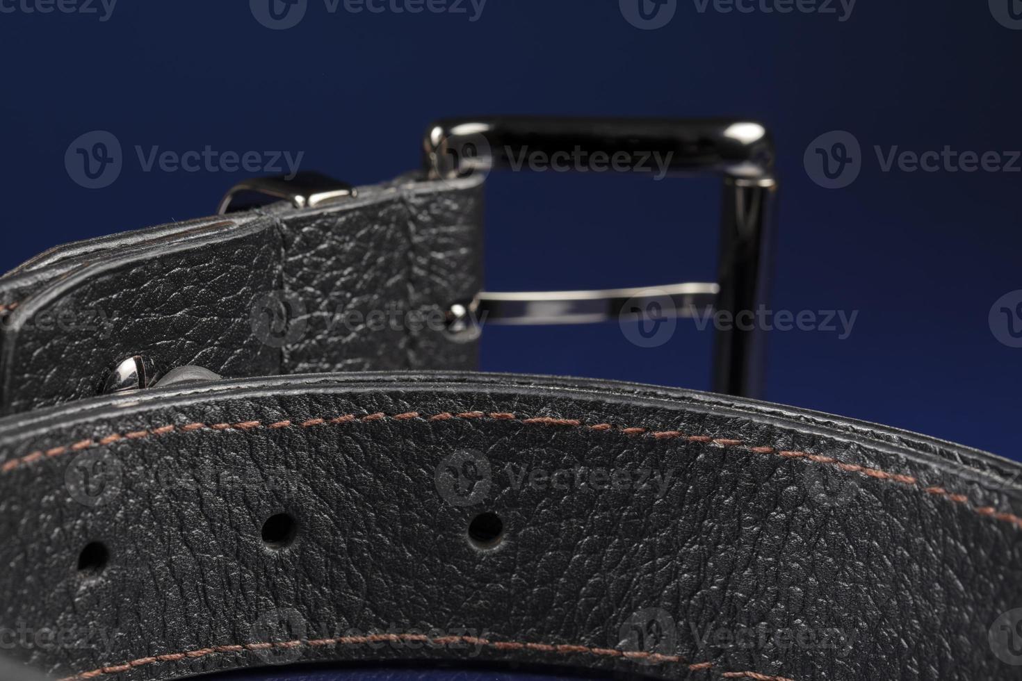 Black leather belt on a dark blue background. photo