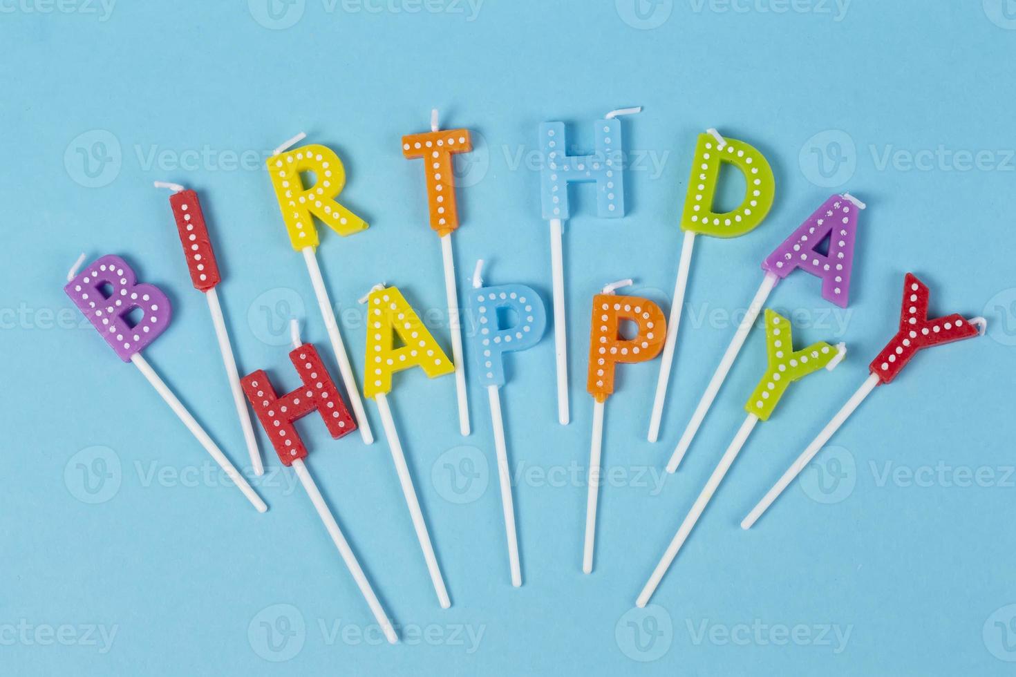 Colorful candles in letters with Happy Birthday lettering isolated on blue background photo