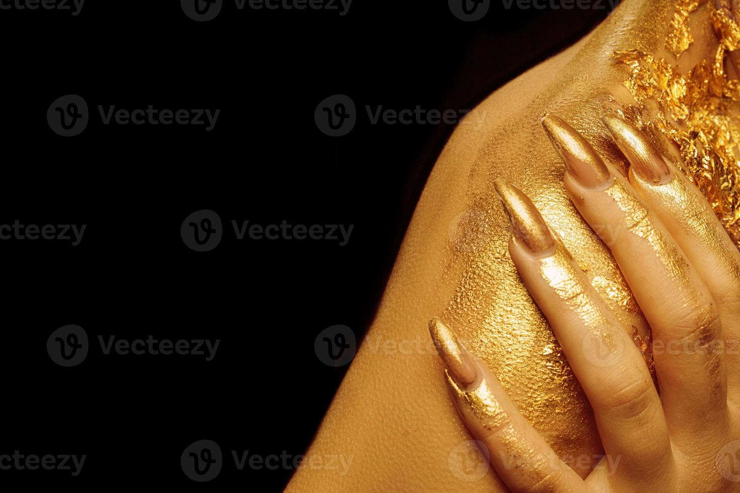 On the shoulder, fingers with golden manicure on a black background. photo