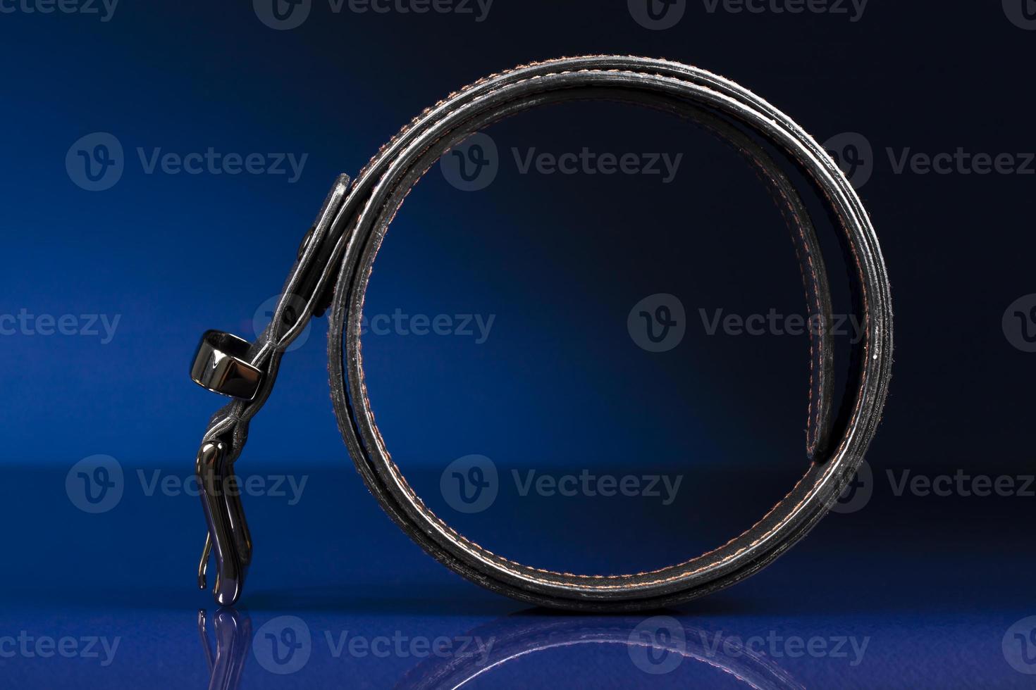Black leather belt on a dark blue background. photo