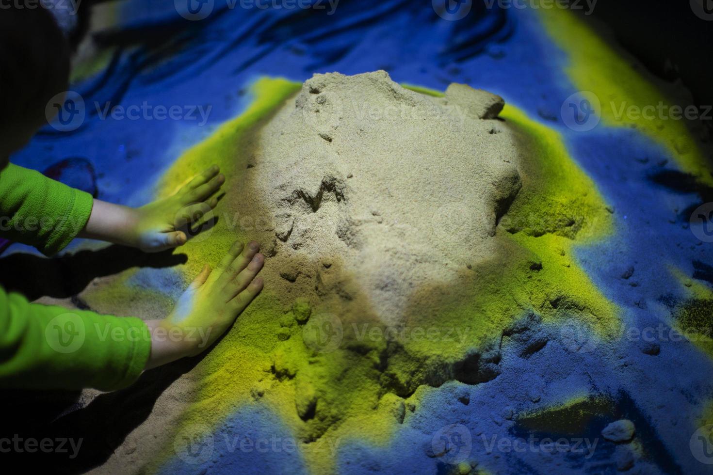 Background of multi-colored sand and children's hands. photo