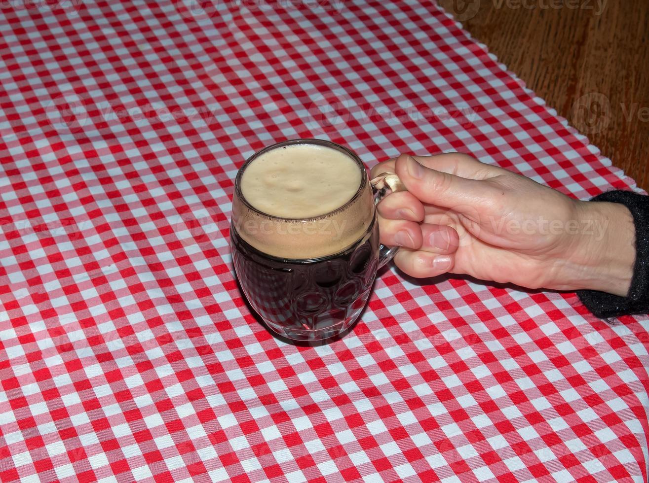 una jarra de cerveza sobre una mesa cubierta con un mantel a cuadros rojos. foto