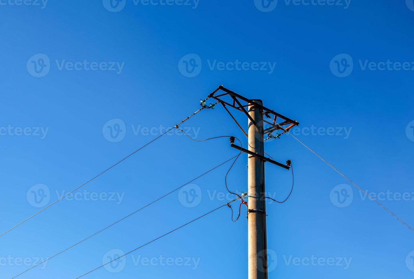 poste eléctrico con un cable lineal contra el primer plano del cielo azul. poste eléctrico de potencia. foto