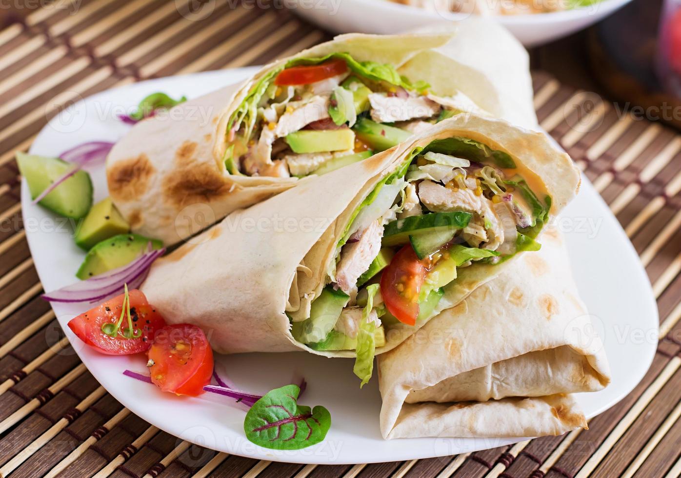 Fresh tortilla wraps with chicken and fresh vegetables on plate photo