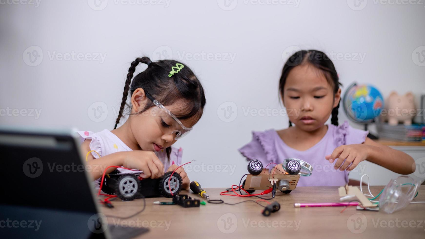 Asian students learn at home by coding robot cars and electronic board cables in STEM, STEAM, mathematics engineering science technology computer code in robotics for kids' concepts. photo