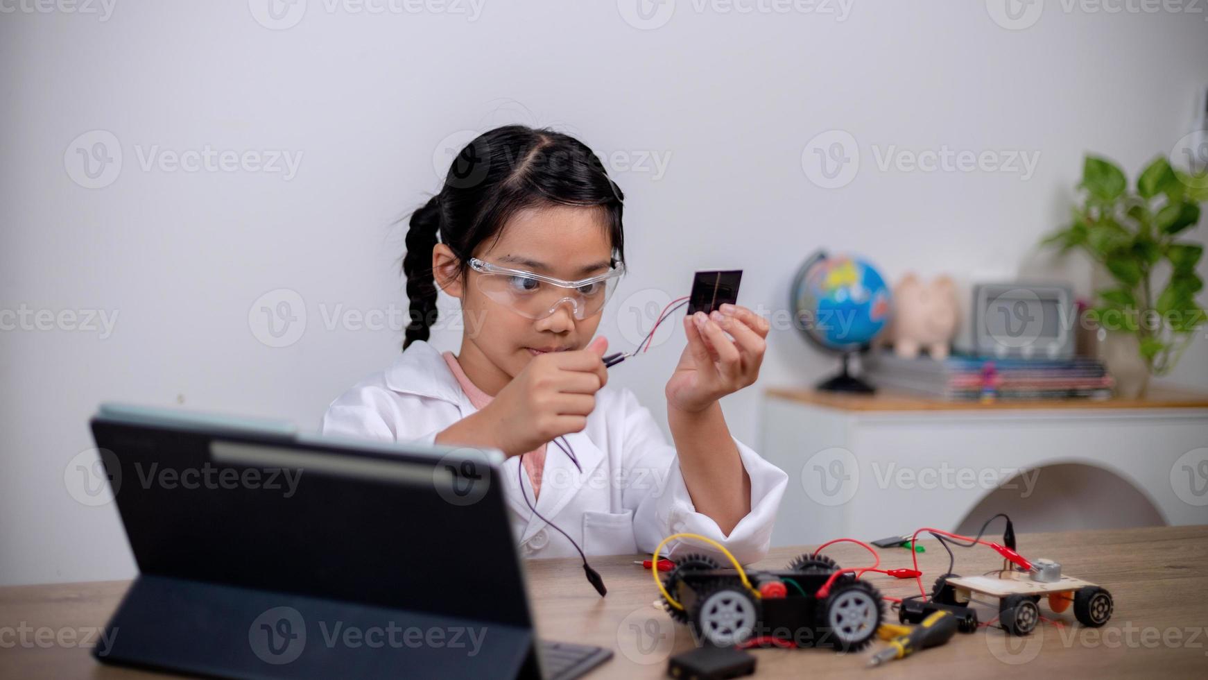 Asian students learn at home by coding robot cars and electronic board cables in STEM, STEAM, mathematics engineering science technology computer code in robotics for kids' concepts. photo