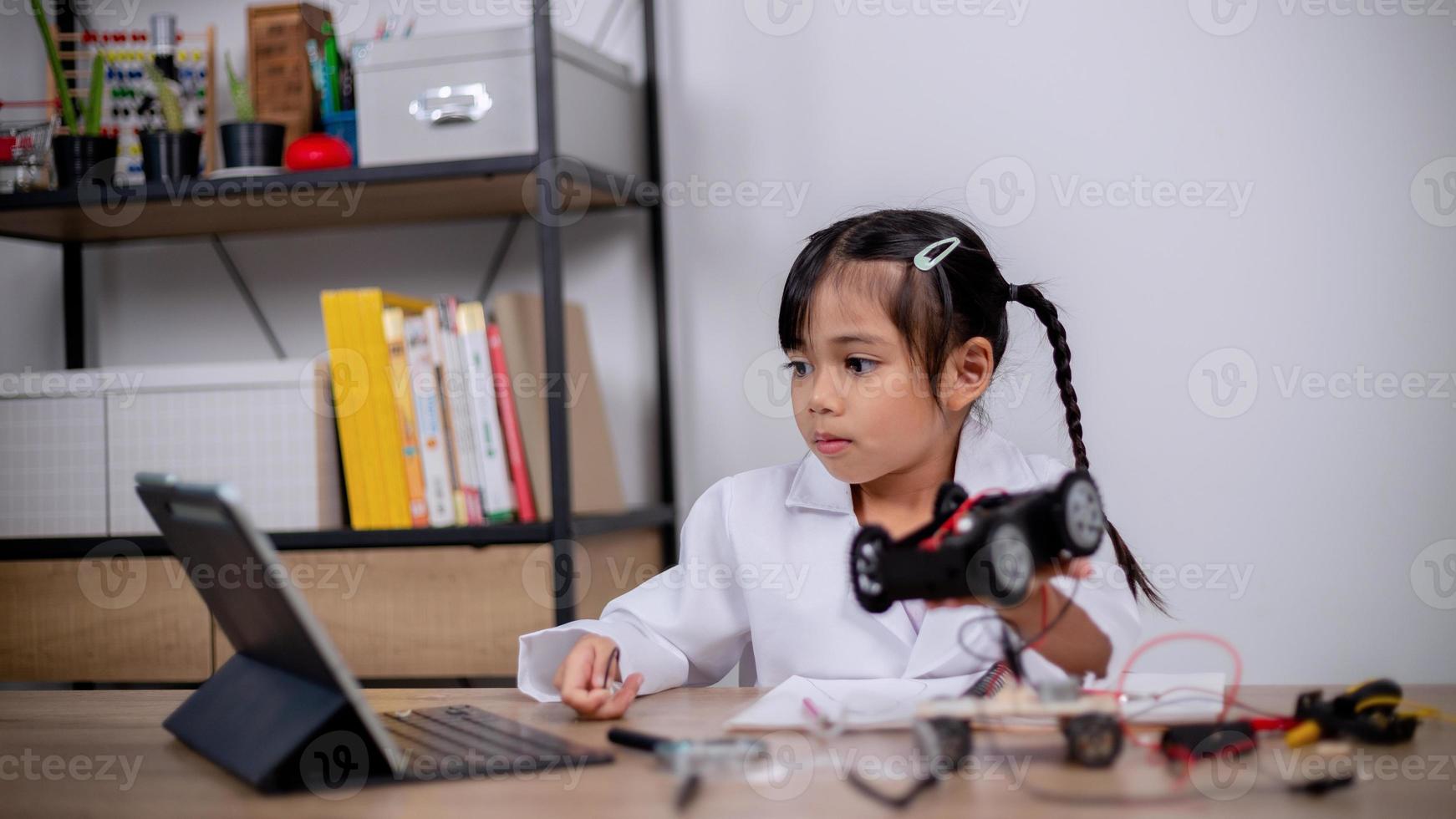 Asian students learn at home by coding robot cars and electronic board cables in STEM, STEAM, mathematics engineering science technology computer code in robotics for kids' concepts. photo