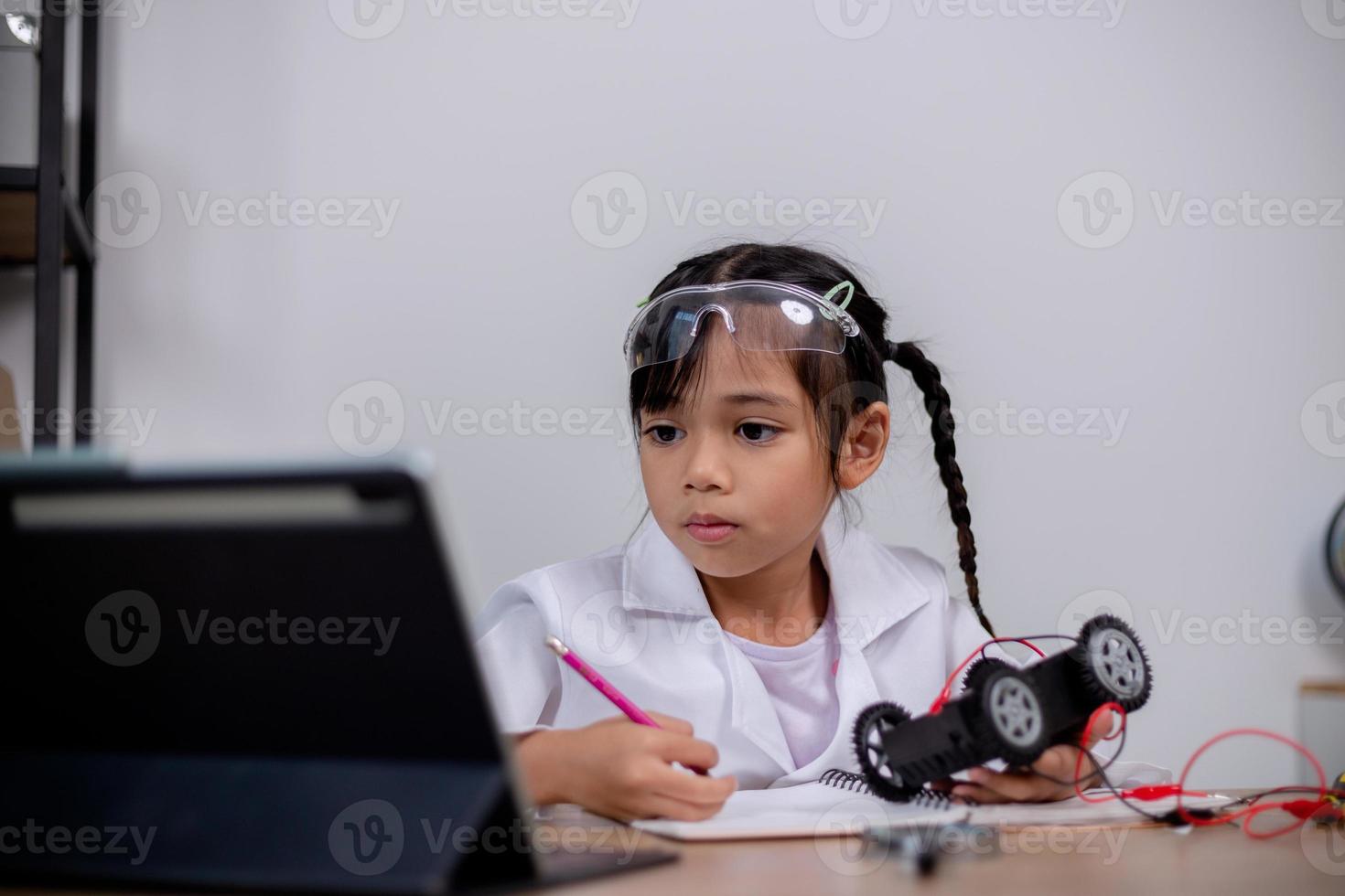 Asian students learn at home by coding robot cars and electronic board cables in STEM, STEAM, mathematics engineering science technology computer code in robotics for kids' concepts. photo