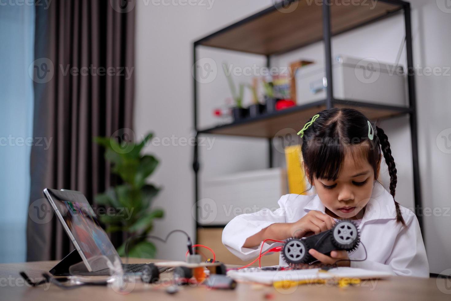 Asian students learn at home by coding robot cars and electronic board cables in STEM, STEAM, mathematics engineering science technology computer code in robotics for kids' concepts. photo
